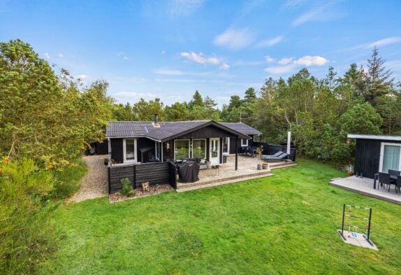 Hyggeligt træsommerhus på stor grund omkranset af træer